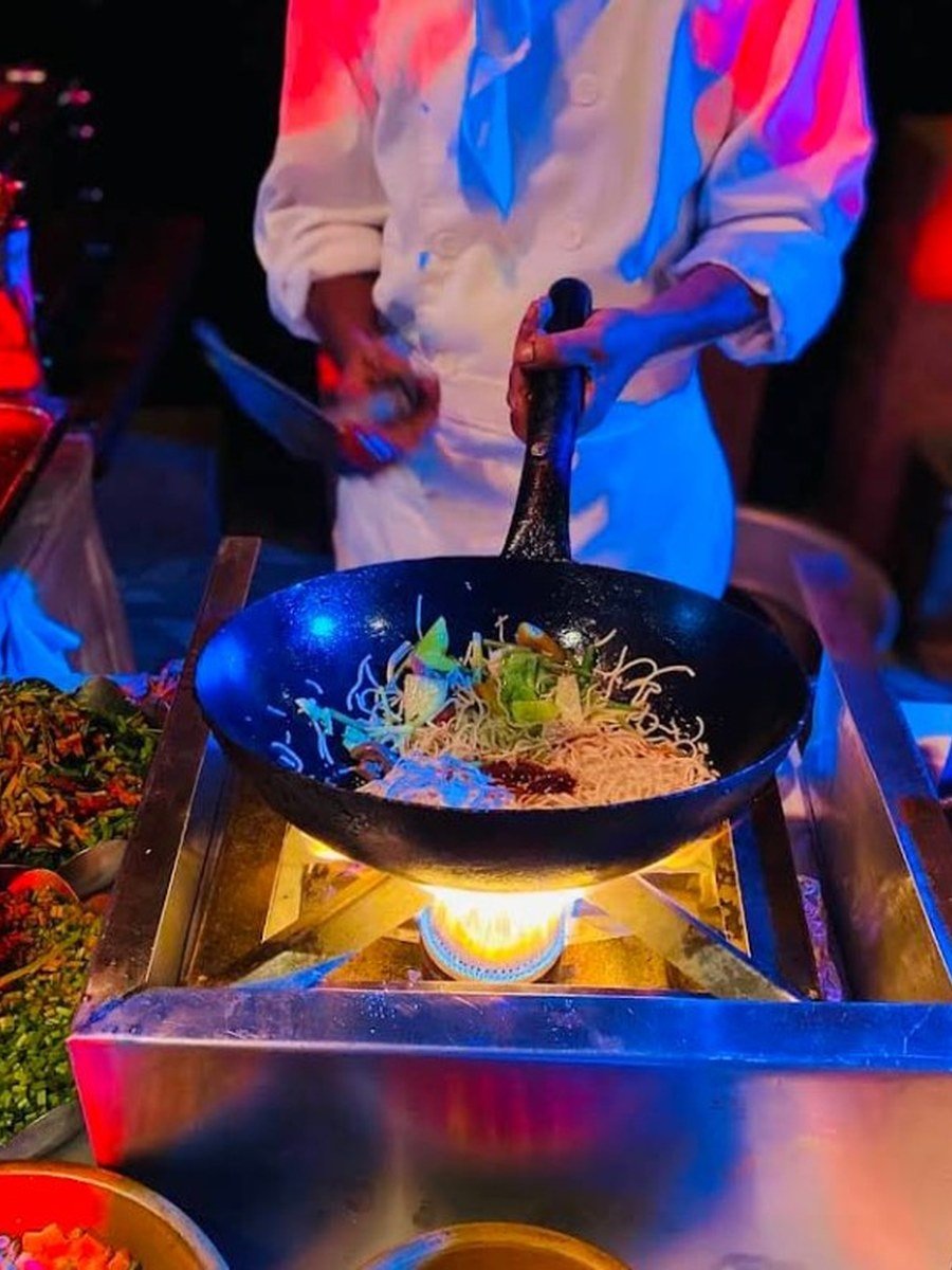 Chef at a live wok and noodle counter with open flame — Abhijat Catering live counters West Bengal